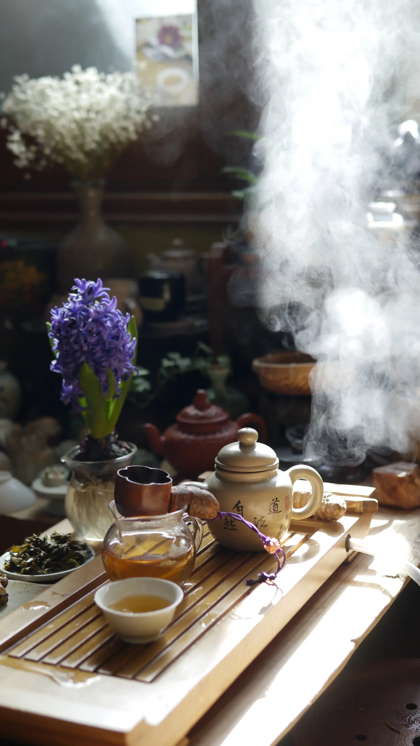 Tasse et théière chaude sur un socle en bois, brume lumineuse autour, fleurs violettes en vase, ambiance zen et spirituelle.