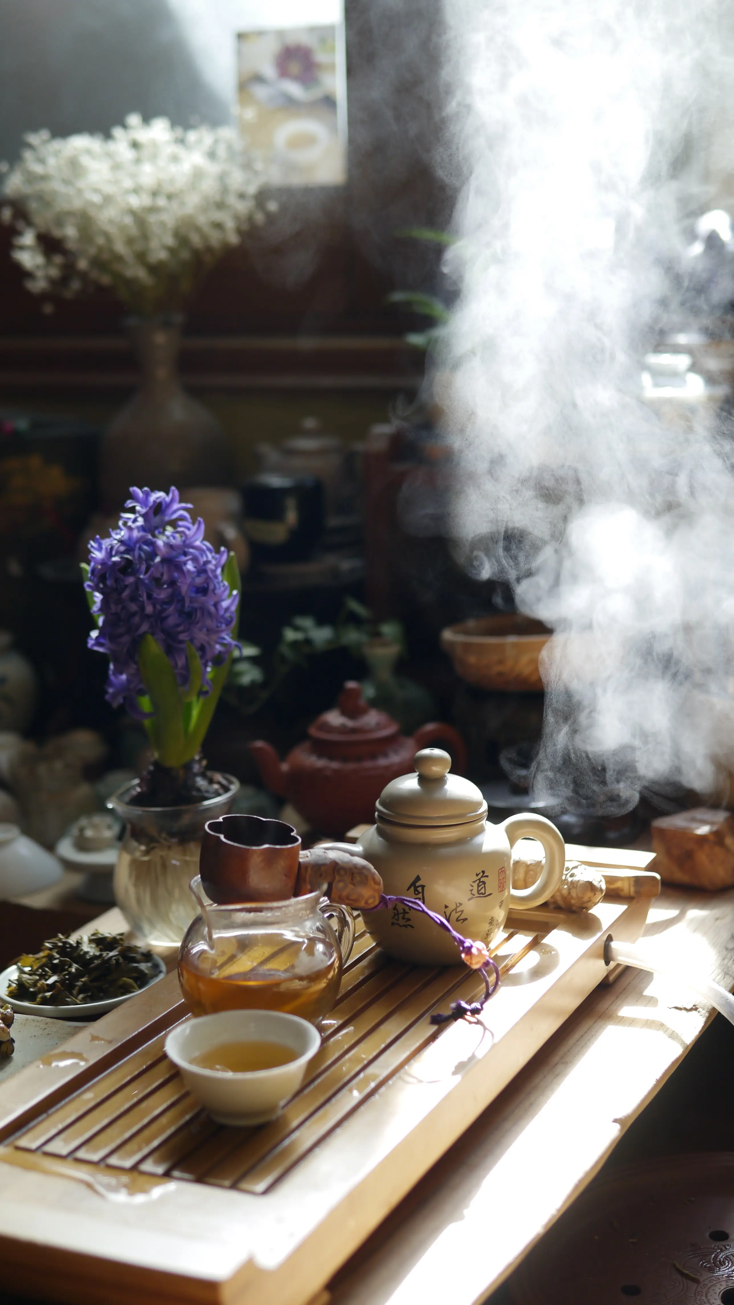 Tasse et théière chaude sur un socle en bois, brume lumineuse autour, fleurs violettes en vase, ambiance zen et spirituelle.